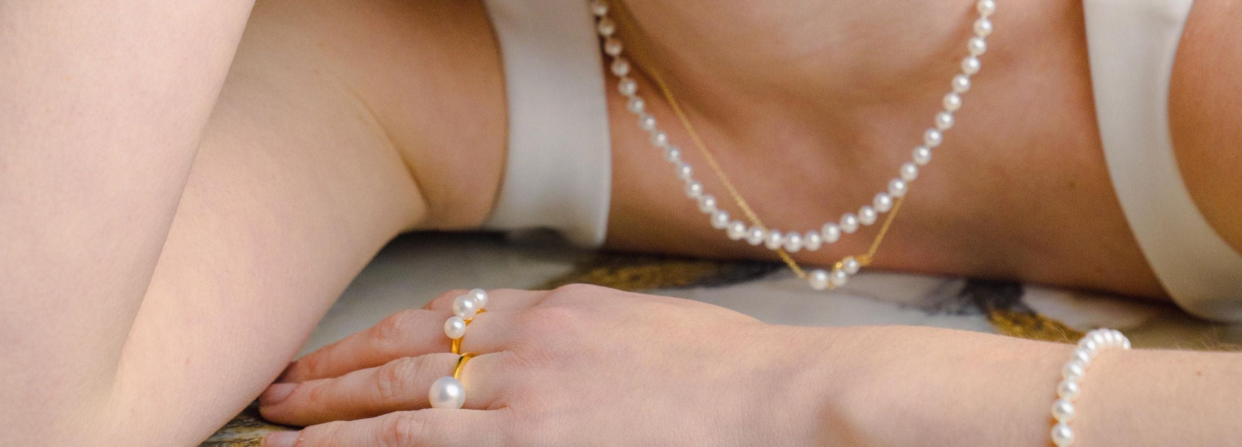 Mujer con collar de perlas, pulsera, anillos y colgante de perlas